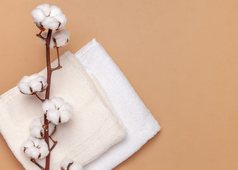 Сotton towels and a sprig of cotton on a beige background. Top view, copy 