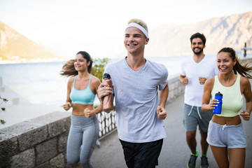 Happy fit people running and jogging together in summer sunny nature