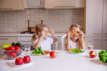 two blonde girls playing with pepper in the kitchen