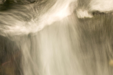 Blurred abstract background of running water. The flow of water in a mountain river.