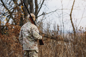 Hunter handsome guy with weapon. Hunter spend leisure hunting. Hunting equipment. Brutal masculine hobby. Man observing nature background. Hunter hold rifle. Safety measures. Natural environment.