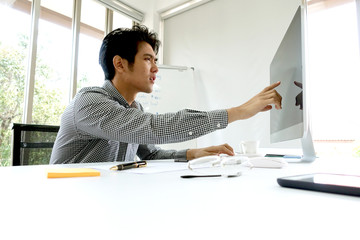 Asian businessman looks confuse and pointing at his computer. For corporate, business, finance,...