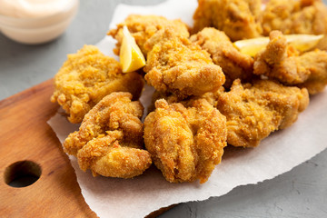 Homemade traditional japanese fried chicken Karaage on a rustic wooden board over gray background, low angle view. Closeup.