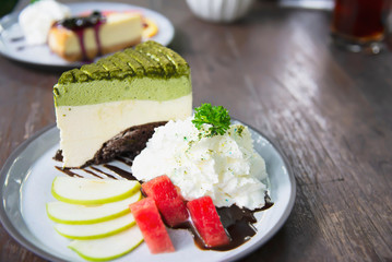 Colorful green tea favor cake with well decorated fruit pieces and whipped cream in white plate - cake recipe menu concept