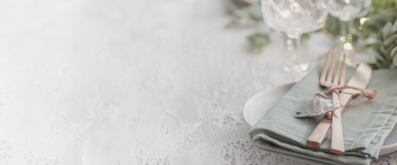 Nordic Festive tableware for Christmas and New Year celebration. Gold cutlery and green linen napkin on cement background for large banner. Kinfolk style © vasanty