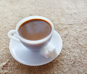 White coffee cup with rich coffee on a textile background