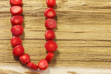 Red coral necklace on a wooden surface. Copy space