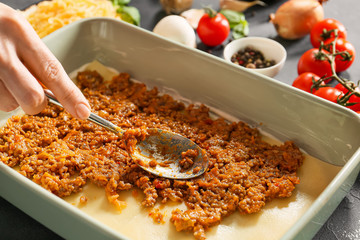 Woman cooking tasty lasagna, closeup
