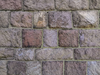 Wall of rectangular and square blocks in different tones of pink and beige. Surface of old stones,...