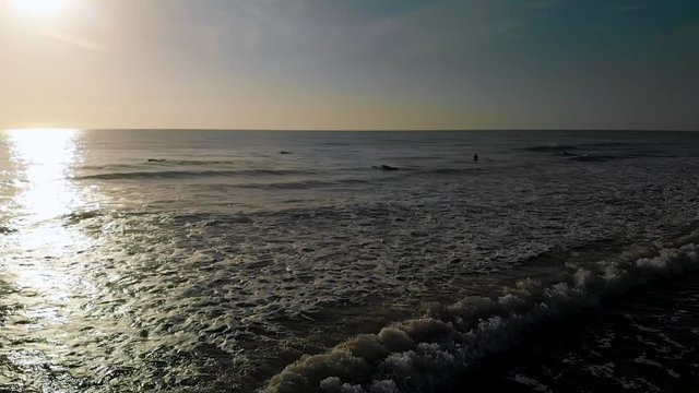 Whitewash waves splash onto a sandy beach in Florida during a sunrise walk on Coco Beach