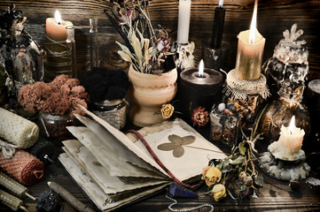 Witch table with magic objects, four-leaf clover, candles and open diary.