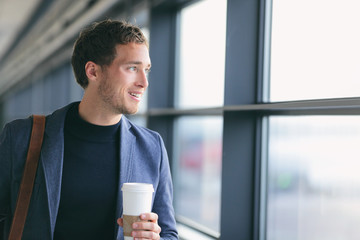 Businessman drinking coffee walking in airport. Casual urban professional smiling happy wearing suit jacket holding disposable coffee cup on travel. Handsome male model in his twenties.