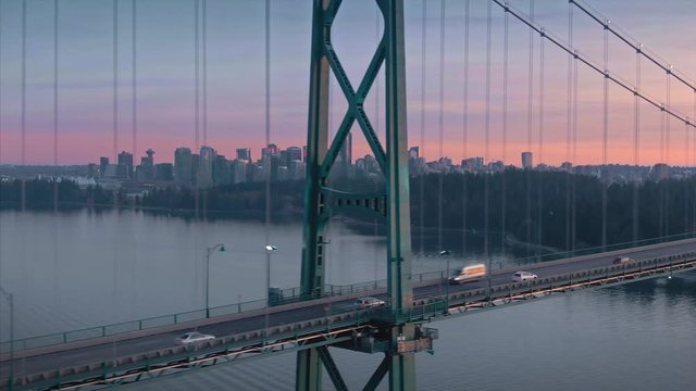 Aerial of traffic crossing Lions Gate Bridge at sunset. In the background is the city skyline. Vancouver, British Columbia, Canada
