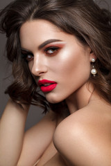 Luxury sexy brunette model with bright professional make up, coral eyeshadows, long lashes and red lips.
