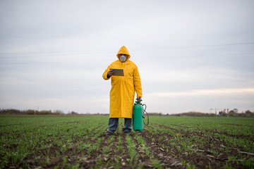 Farmer in yellow coat, controls the work in the field over its tablet.