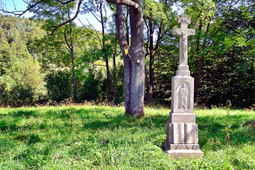 Old stone cross in meadow and trees of Low Beskids, Poland