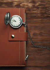 Leather diary and retro watch on a  wooden brown background photo