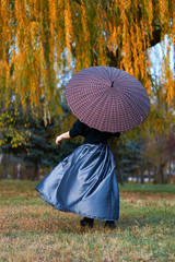 Beautiful elegant woman spinning and posing with umbrella in autumn city park