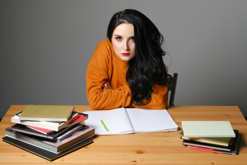 young woman is sitting at the books. education