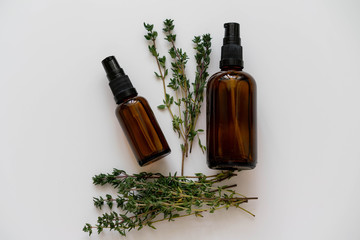 Organic cosmetic products flat lay photo with glass bottles and fresh thyme herb, horizontal orientation.