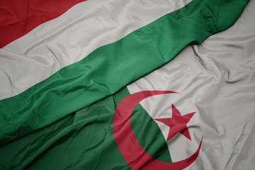 waving colorful flag of algeria and national flag of hungary.