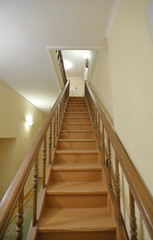 Old brown wood staircase with a handrail in a building without an elevator
