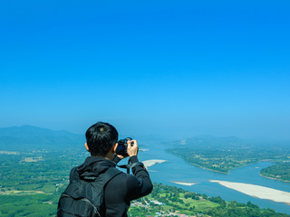 Traveler man taking nature photo of river and mountain landscape.