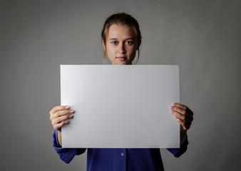 Young woman in blue is holding white paper.