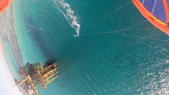 Aerial footage of a man kitesurfing near a massive oil rig in the sea, Egypt, 4k