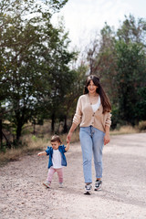 Obraz premium Happy mother looking at camera with her daughter walking together in the nature