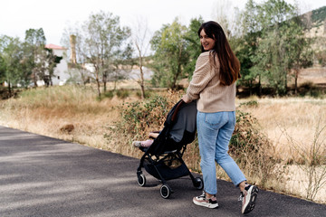 Happy family walking with a baby cart in the nature