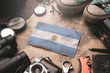 Fototapeta na wymiar Argentina Flag Between Traveler's Accessories on Old Vintage Map. Tourist Destination Concept.