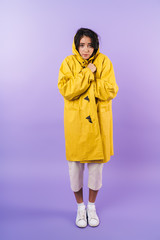 Frozen cute brunette woman in yellow raincoat