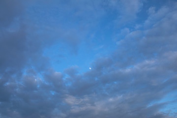 Obraz premium Mystical moon far away on blue evening sky with whirlwind purple clouds