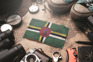 Dominica Flag Between Traveler's Accessories on Old Vintage Map. Tourist Destination Concept.