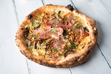 Deliziosa pizza gourmet con spek, gorgonzola, funghi, noci e pistacchio 