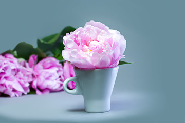 Cup of coffee on a table with a bouquet of pink peonies