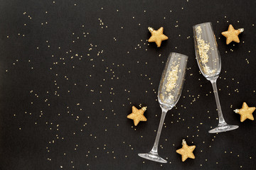 Confetti in the shape of stars poured out glasses of champagne on the black holiday background. Christmas decor. Christmas and new year background. Top view. - obrazy, fototapety, plakaty
