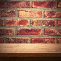 Wooden table against red brick wall, rustic background