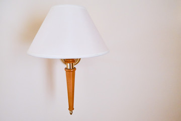 A cone lamp with a wooden leg on the wall in a white room. Part of the interior in the home room, background. Interior empty wall background with lamps over.