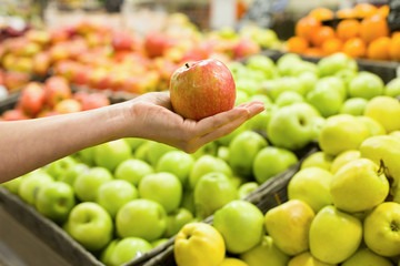 Woman's hand choosing apple in the market. Concept of healthy food, bio, vegetarian, diet.