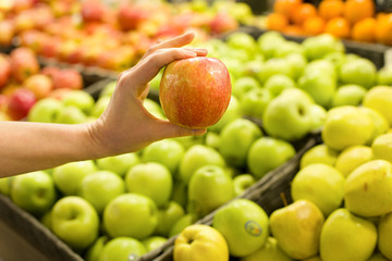 Woman's hand choosing apple in the market. Concept of healthy food, bio, vegetarian, diet.