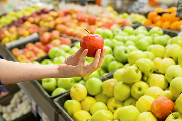 Female hand choosing apple in the market. Concept of healthy food, bio, vegetarian, diet.