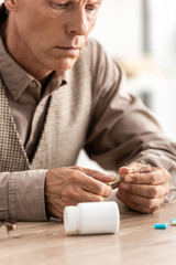 cropped view of sick senior man looking at pills