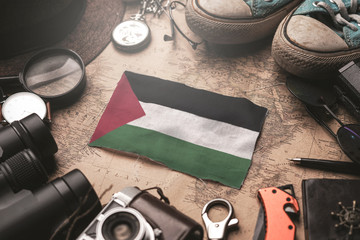 Fototapeta na wymiar Palestine Flag Between Traveler's Accessories on Old Vintage Map. Tourist Destination Concept.