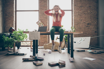 Full length photo of mad busy freelancer secretary with negative mood made mistake fired sit on table feel overworked yell touch blonde hair in messy office workstation loft