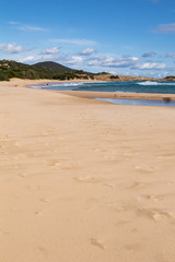 Mediterranean sea coast with beach, sun and cloudy sky. Sea and vacation in winter, yellow beach and waves that reach the shoreline. Blue and emerald green water