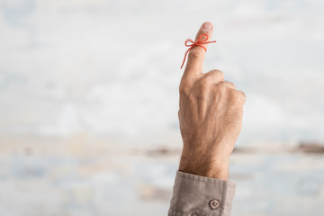cropped view of senior man with red bow on finger as reminder