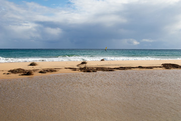 Mediterranean sea coast with beach, sun and cloudy sky. Sea and vacation in winter, yellow beach and waves that reach the shoreline. Blue and emerald green water
