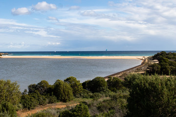 Mediterranean sea coast with beach, sun and cloudy sky. Sea and vacation in winter, yellow beach and waves that reach the shoreline. Blue and emerald green water